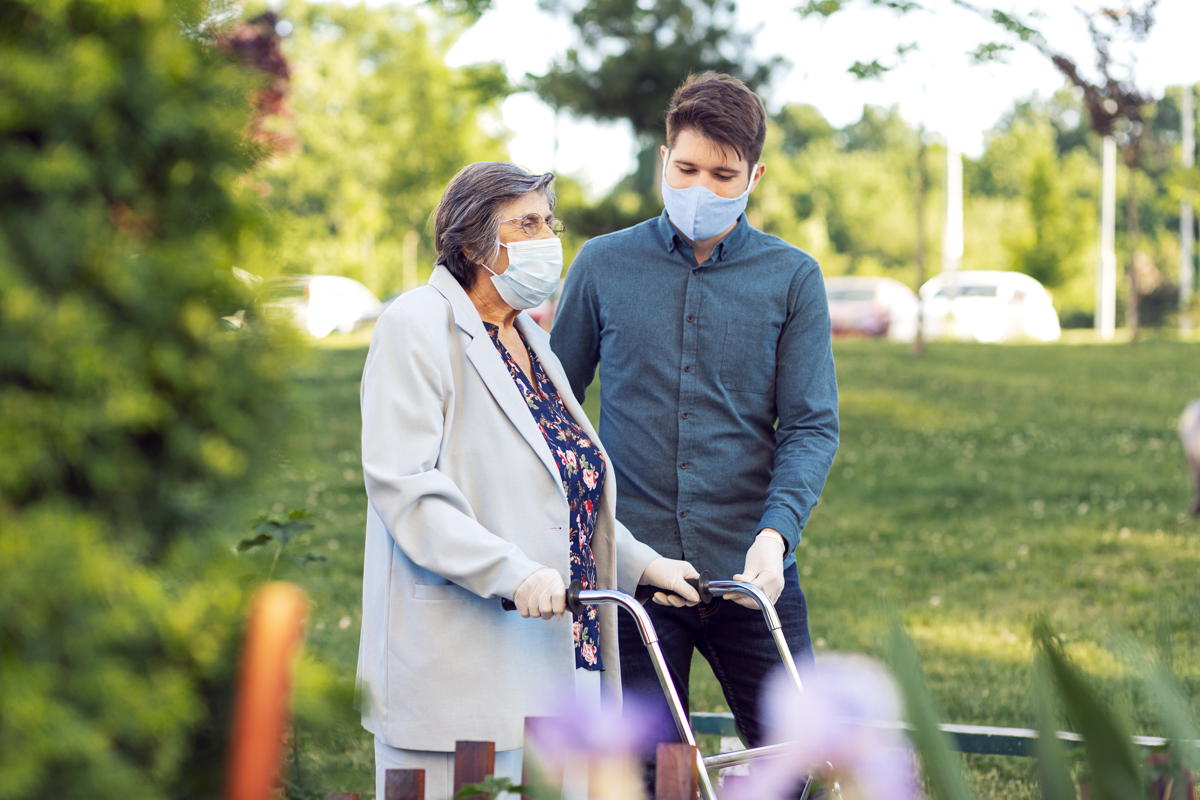 senior woman wearing a mask is helped by a young man wearing a mask