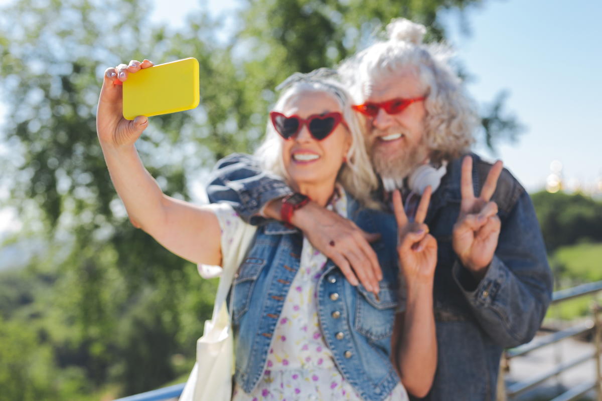 2 baby boomers smile as they take a selfie with a smartphone