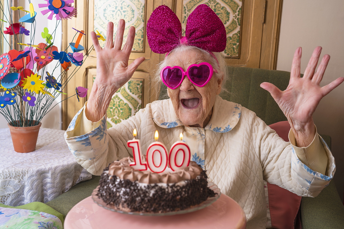 representing longevity, a woman celebrates her 100th birthday with a cake