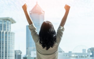woman raises her arms in victory representing women-owned business leaders