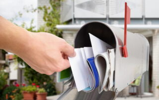 a hand reaches for letters and direct mail marketing pieces in a mailbox